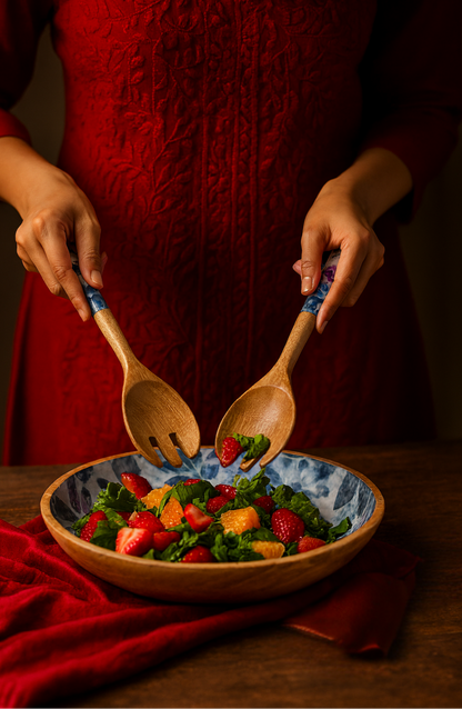 Person in a red dress using wooden spoons to serve a colorful salad from a bowl.